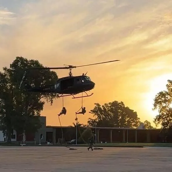 Efectivos del Ejército Argentino ejecutan un descenso táctico con cuerdas en la pista de la Guarnición Ejército Arana durante la caída del sol.
